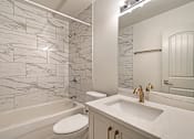 Thumbnail 64 of 219 - A white bathroom with a marble tile wall and a white toilet.