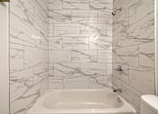 Thumbnail 63 of 219 - A white bathroom with a marble tile wall.