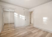 Thumbnail 60 of 219 - A room with a wooden floor and white walls, with a door and a window.
