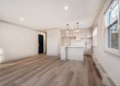 Thumbnail 31 of 219 - A room with wooden floors and white walls, with a window on the right side.