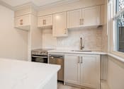 Thumbnail 52 of 219 - A kitchen with white cabinets and marble countertops.