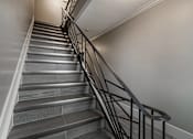 Thumbnail 201 of 219 - A staircase with a black metal railing and grey steps.