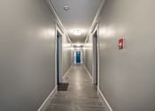 Thumbnail 199 of 219 - A long hallway with doors at the end and a fire extinguisher on the wall.