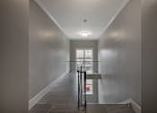 Thumbnail 192 of 219 - A hallway with a black suitcase on the floor.