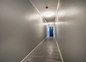 Thumbnail 190 of 219 - A long hallway with a blue door at the end.