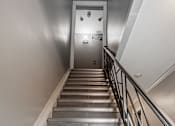 Thumbnail 189 of 219 - A staircase with a metal railing and stone steps leading to a door.