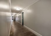 Thumbnail 211 of 219 - A long hallway with a wooden floor and white walls.
