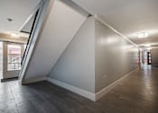 Thumbnail 210 of 219 - A hallway with a staircase on the left side and a door on the right side.