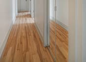 Thumbnail 175 of 219 - A long hallway with wood floors and white walls.