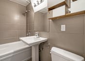 Thumbnail 166 of 219 - A white sink is on a stand in a bathroom with a white toilet and a bathtub.