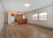 Thumbnail 184 of 219 - A room with wooden floors and a kitchen area in the background.