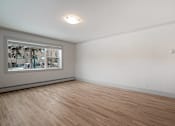 Thumbnail 182 of 219 - A room with wooden flooring and a window showing a view of trees and buildings outside.