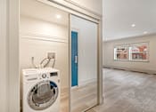 Thumbnail 125 of 219 - A washing machine is sitting in a room with a blue door.