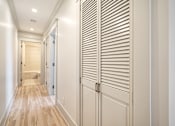 Thumbnail 112 of 219 - A hallway with a wooden floor and white walls.