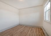 Thumbnail 103 of 219 - A room with wooden flooring and a window on the right side.