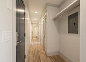 Thumbnail 99 of 219 - A long hallway with wood floors and white walls.