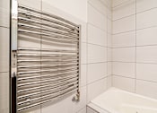 Thumbnail 101 of 219 - A white tiled bathroom with a white bathtub and a chrome towel rack.