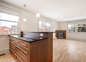 Thumbnail 114 of 219 - A kitchen with a black counter top and wooden floors.
