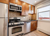 Thumbnail 113 of 219 - A kitchen with a stainless steel refrigerator, microwave, oven, and cabinets.