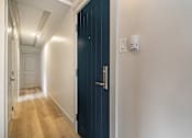 Thumbnail 77 of 219 - A hallway with a blue door and white walls.
