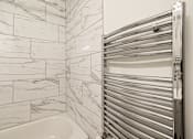 Thumbnail 84 of 219 - A white tiled bathroom with a closed towel warmer.