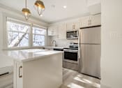 Thumbnail 80 of 219 - A kitchen with a stainless steel refrigerator and a white countertop.