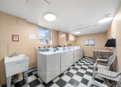 Thumbnail 24 of 33 - a public restroom with sinks and chairs and a checkered floor