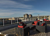 Thumbnail 20 of 27 - A rooftop patio with black furniture and a view of the city.