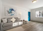 Thumbnail 151 of 219 - A living room with a grey couch and a blue abstract painting on the wall.