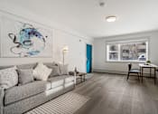 Thumbnail 150 of 219 - A living room with a grey couch and a painting on the wall.