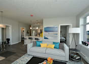 Thumbnail 8 of 42 - A living room with a grey couch and a painting on the wall.