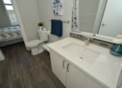 Thumbnail 13 of 42 - A bathroom with a toilet, sink, and mirror.