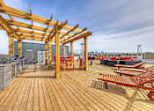 Thumbnail 16 of 27 - A wooden deck with red chairs and tables.