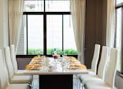 Thumbnail 11 of 11 - A dining table set for a meal with white chairs and a view of the outside.