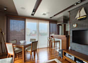 Thumbnail 4 of 11 - A living room with a television and a dining table.