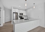 Thumbnail 2 of 27 - A modern kitchen with a white countertop and stainless steel appliances.