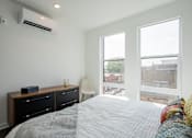 Thumbnail 27 of 66 - Primary bedroom with city views and minimalist design in The Rail’s luxury apartments in Bound Brook, offering comfort and tranquility.