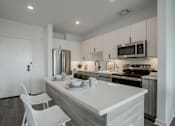 Thumbnail 18 of 66 - Luxury apartment kitchen and living area at The Rail at Bound Brook, NJ—featuring modern apartment amenities, quartz countertops, and stainless steel appliances in a spacious open-concept layout.