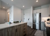 Thumbnail 19 of 66 - Entryway and modern kitchen with woodgrain cabinets, quartz countertops, and an island at The Rail Bound Brook—combining style with functionality.