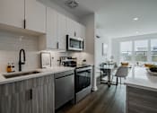 Thumbnail 15 of 66 - Spacious kitchen and dining space in a luxury Bound Brook apartment with sleek finishes, breakfast island seating, and bright natural lighting.