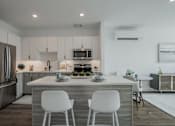 Thumbnail 17 of 66 - Contemporary kitchen at The Rail featuring white cabinetry, subway tile backsplash, stainless steel appliances, and natural light from large windows.