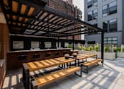 Thumbnail 10 of 72 - Outdoor bar and shaded picnic tables at The Rail at Bound Brook—designed for luxury apartment residents in Bound Brook, NJ.