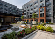 Thumbnail 5 of 72 - Scenic courtyard view at The Rail at Bound Brook with outdoor lounge areas, gardens, and modern architecture—luxury apartments in Bound Brook, NJ.