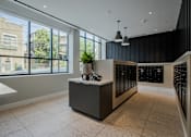 Thumbnail 4 of 33 - A modern mail room lobby with a reception desk and a view of the outside at The Rail at Bound Brook, NJ.