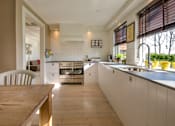 Thumbnail 1 of 17 - A modern kitchen with a wooden table and white cabinets.