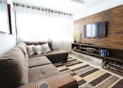 Thumbnail 17 of 18 - a living room with a large brown couch and a flat screen tv on the wall