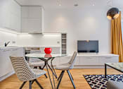 Thumbnail 8 of 17 - A modern kitchen with a glass table and chairs.