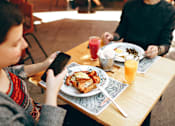 Thumbnail 16 of 17 - A person is sitting at a table with a plate of food and a glass of juice.