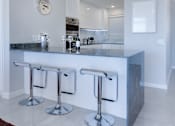Thumbnail 9 of 18 - a kitchen with a long counter and three stools in front of it