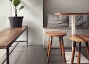 Thumbnail 2 of 17 - A potted plant sits on a table next to a couch with a grey pillow.